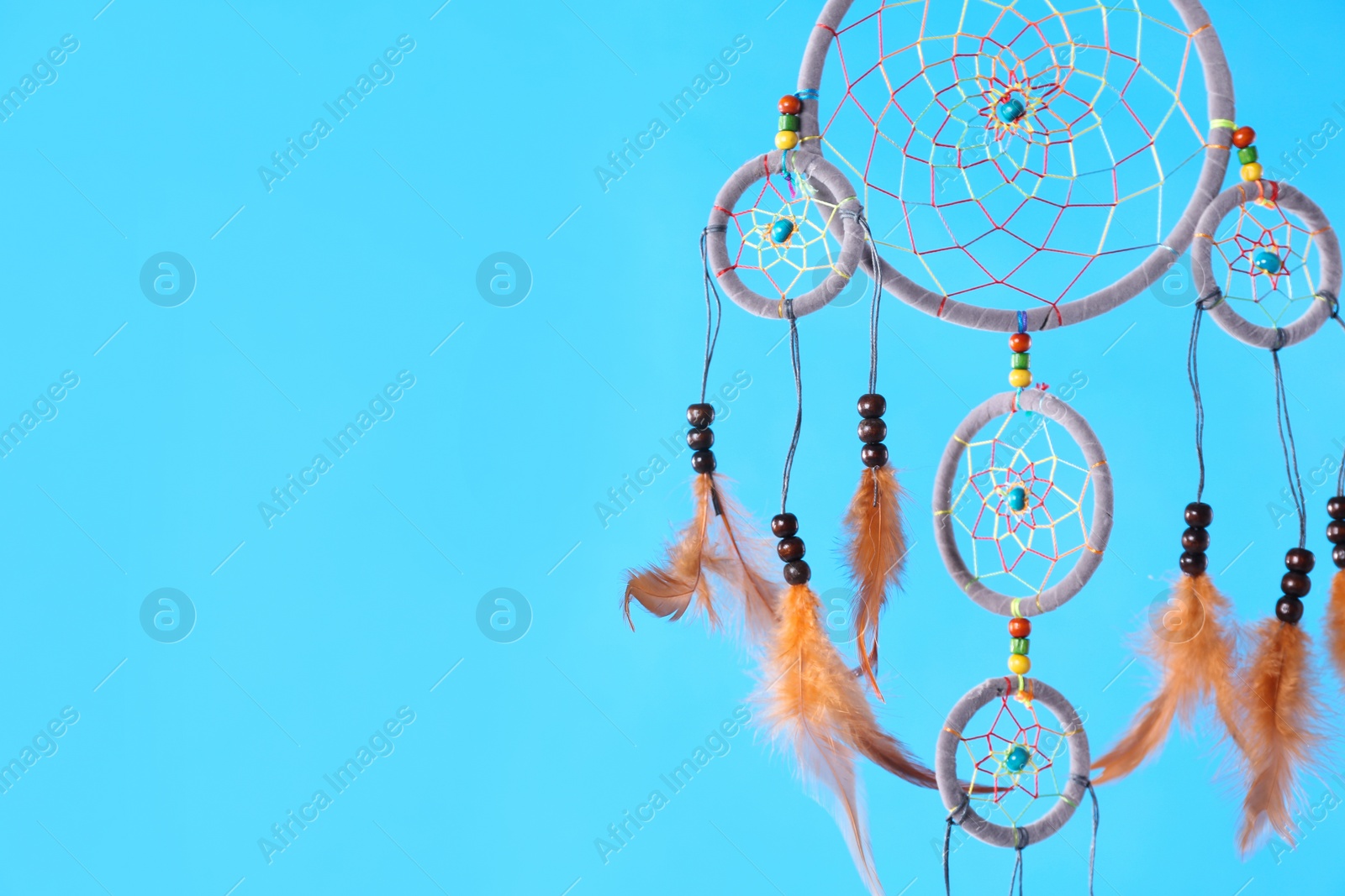 Photo of Beautiful handmade dream catcher on light blue background. Space for text