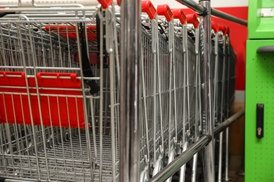 Photo of Many empty shopping carts in supermarket, closeup