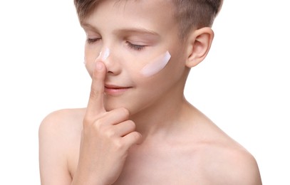 Photo of Smiling boy applying sun protection cream onto his face against white background