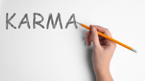 Woman writing word KARMA on white background, closeup, Banner design