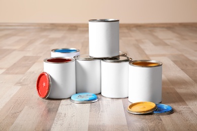 Photo of Cans of paint on wooden floor indoors