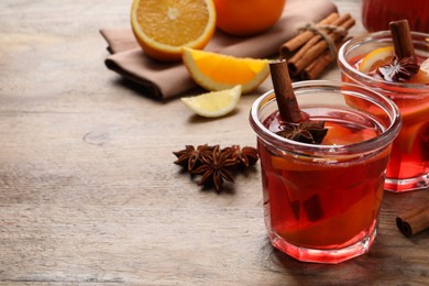 Photo of Aromatic punch drink and ingredients on wooden table, space for text