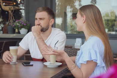 Young man having boring date with talkative girl in outdoor cafe