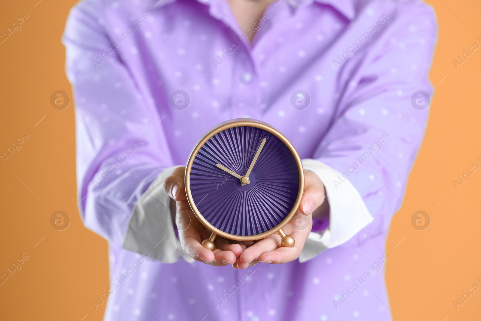 Photo of Young woman holding alarm clock on color background. Time concept