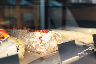 Photo of Delicious meringue roll on counter in bakery shop, closeup. Space for text