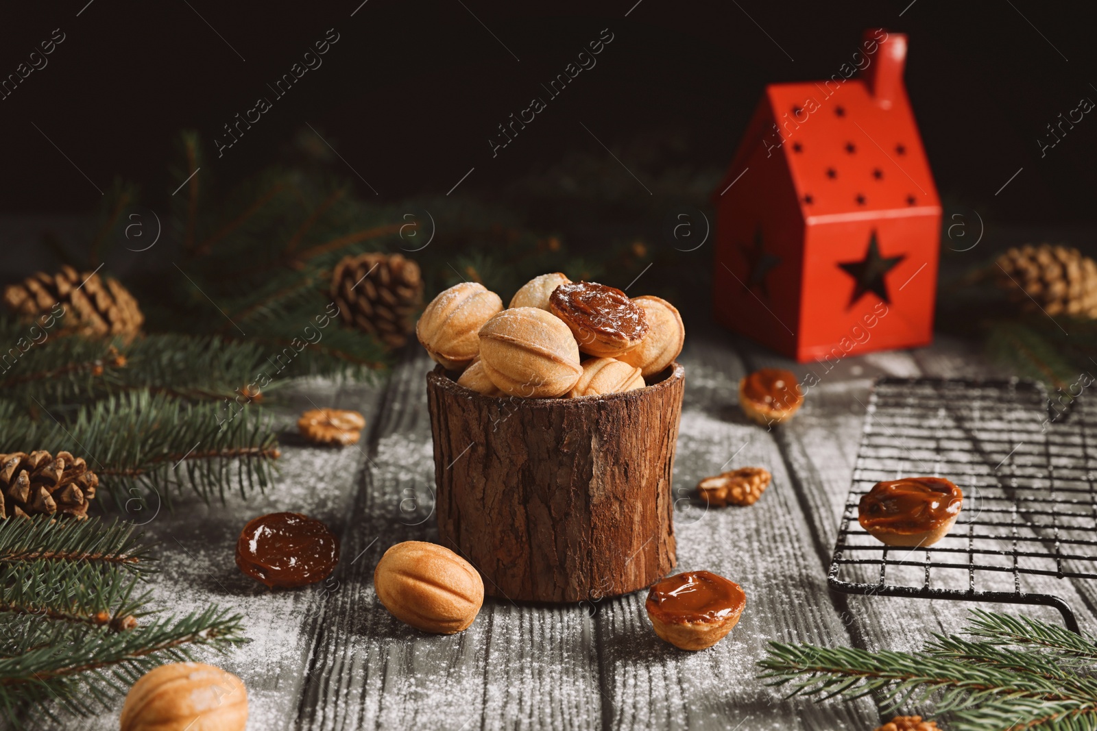 Photo of Homemade walnut shaped cookies with boiled condensed milk, fir branches and cones on wooden table