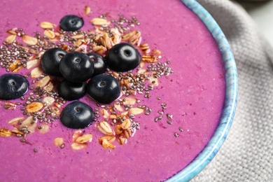 Photo of Delicious acai smoothie with granola and chia seeds in dessert bowl on table, closeup