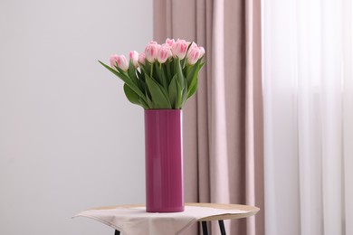 Beautiful bouquet of fresh pink tulips on table indoors