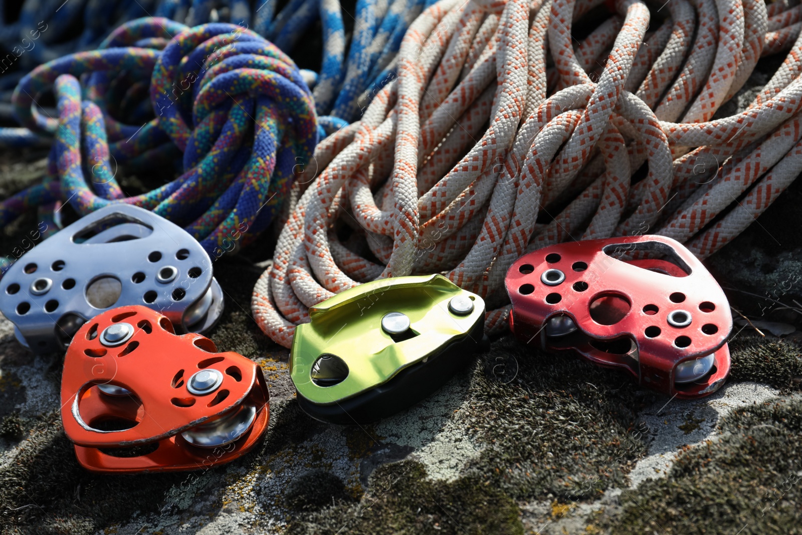 Photo of Different belay devices and ropes on rock, closeup. Climbing equipment