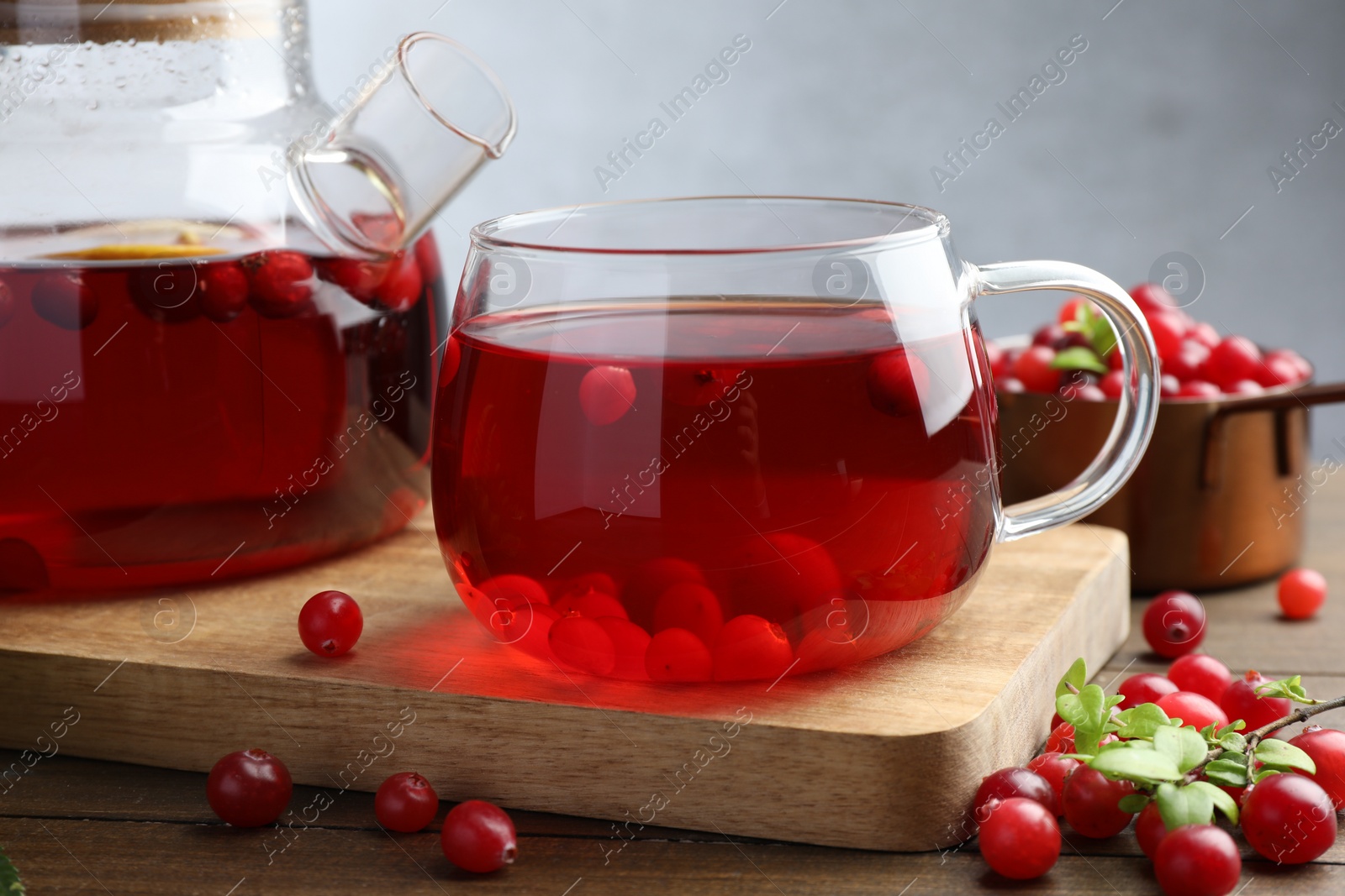 Photo of Tasty hot cranberry tea and fresh berries on wooden table