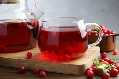 Photo of Tasty hot cranberry tea and fresh berries on wooden table