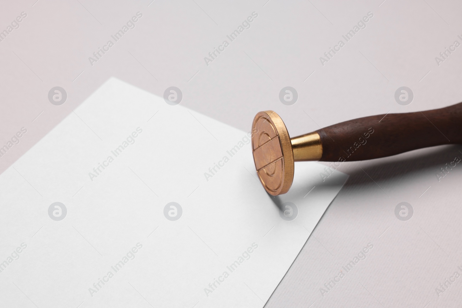 Photo of One stamp tool and sheet of paper on light grey background, closeup. Space for text
