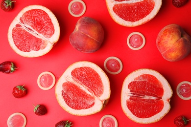 Photo of Flat lay composition with condoms and exotic fruits on red background. Erotic concept