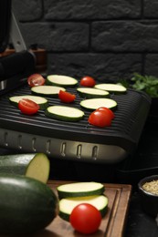 Photo of Electric grill with vegetables on table, closeup