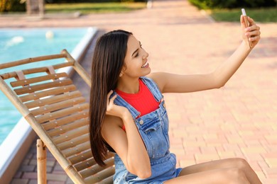 Young woman taking selfie in deck chair outdoors