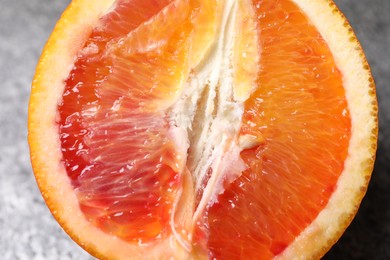 Photo of Half of ripe red orange on grey table, closeup