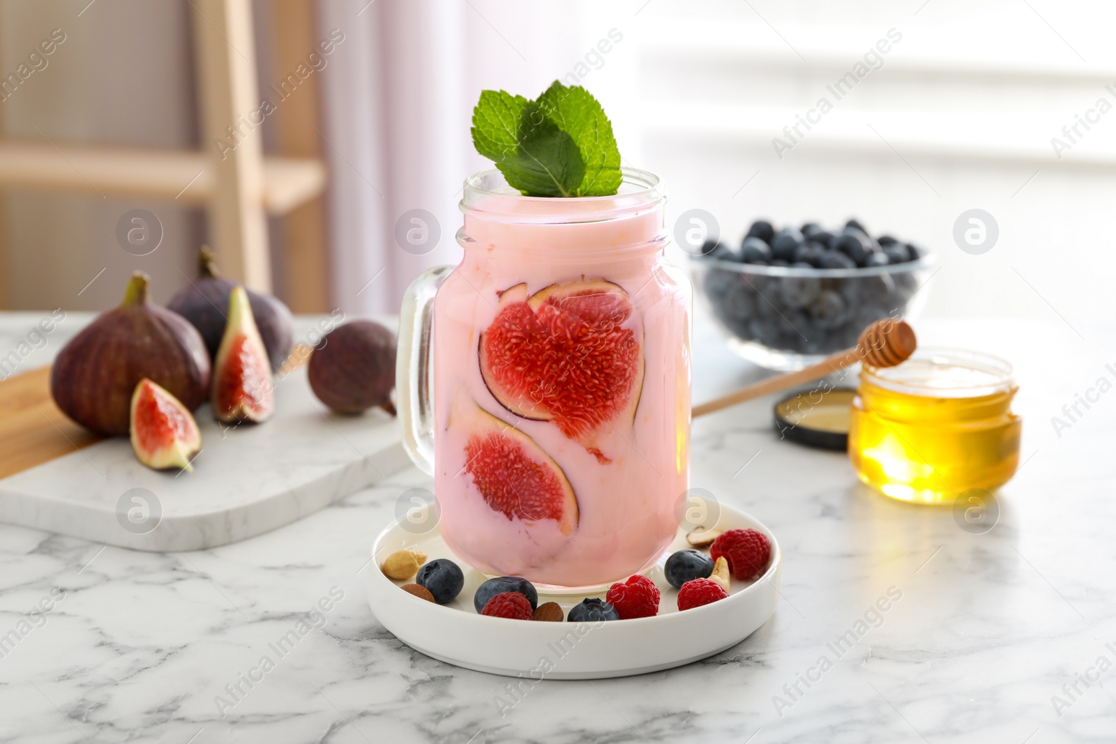 Photo of Delicious fig smoothie in mason jar on white marble table