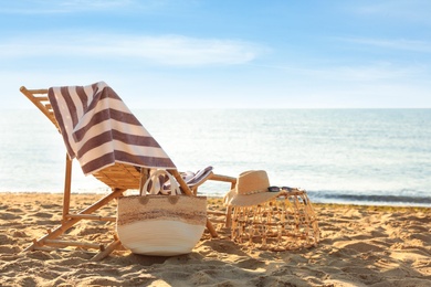 Wooden deck chair and beach accessories near sea. Summer vacation