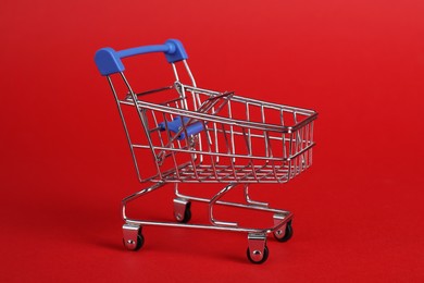 Photo of Small metal shopping cart on red background