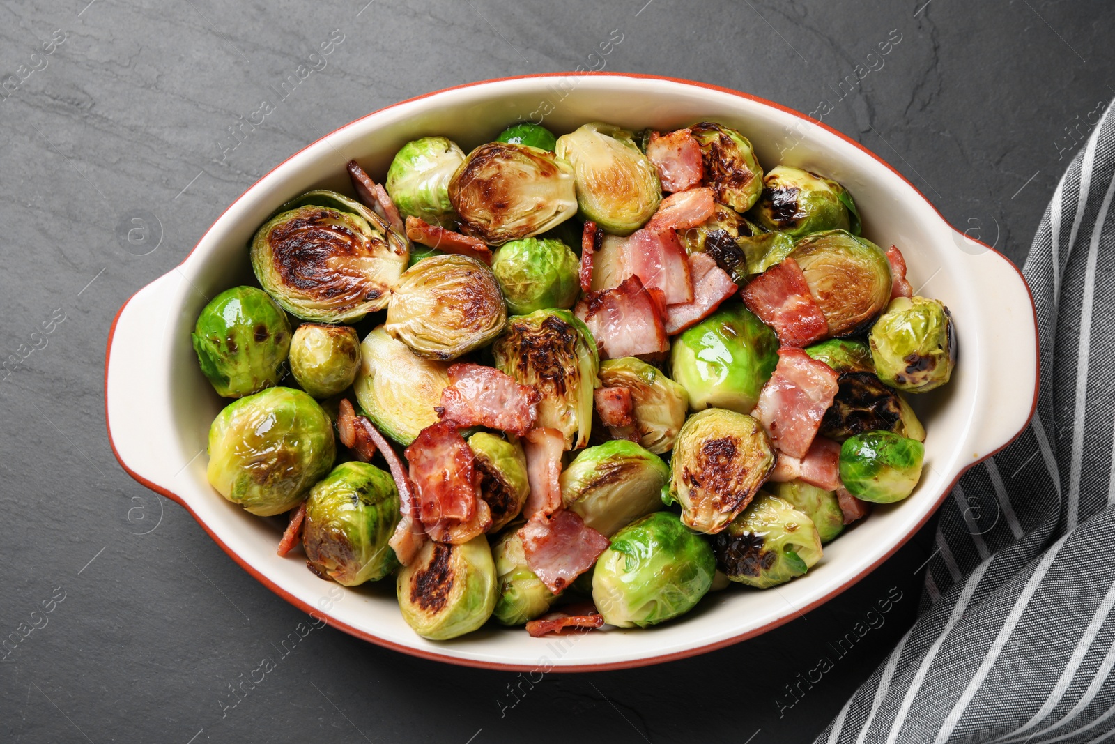 Photo of Delicious Brussels sprouts with bacon in baking pan on grey table, top view