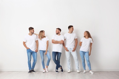 Group of young people in jeans near light wall