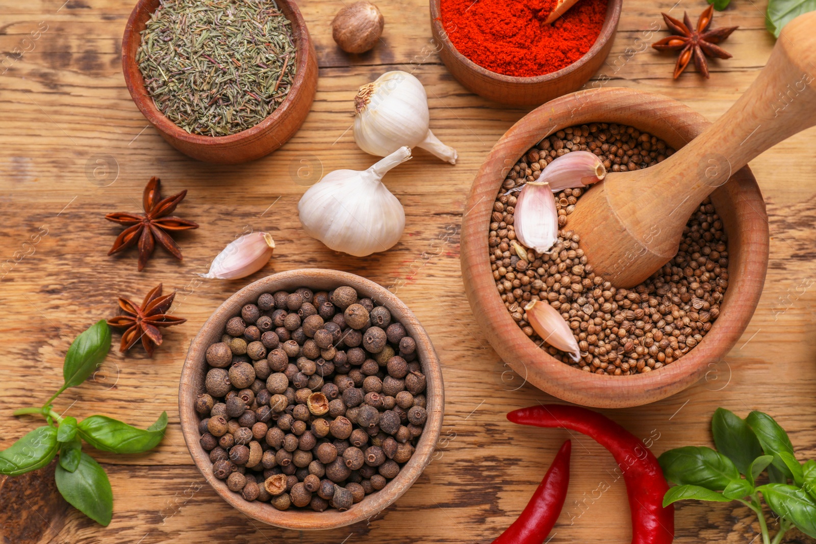 Photo of Mortar with pestle and different spices on wooden table, flat lay