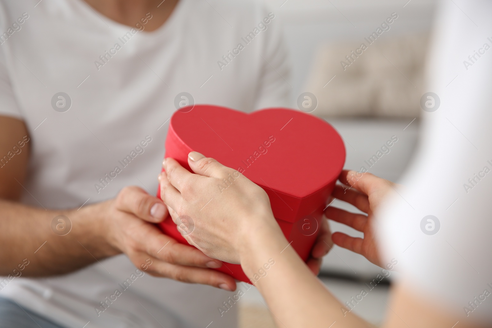 Photo of Man presenting gift to his beloved woman at home, closeup. Valentine's day celebration