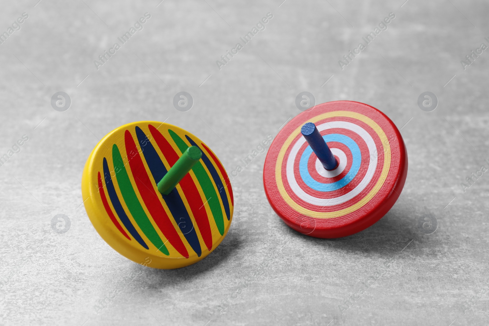 Photo of Bright spinning tops on grey textured background, closeup