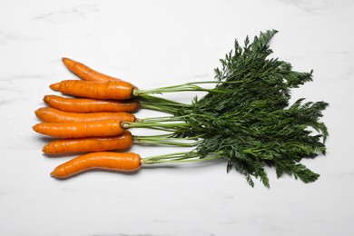 Tasty washed carrots on white marble table, top view