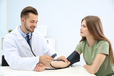 Doctor checking young woman's pulse in hospital