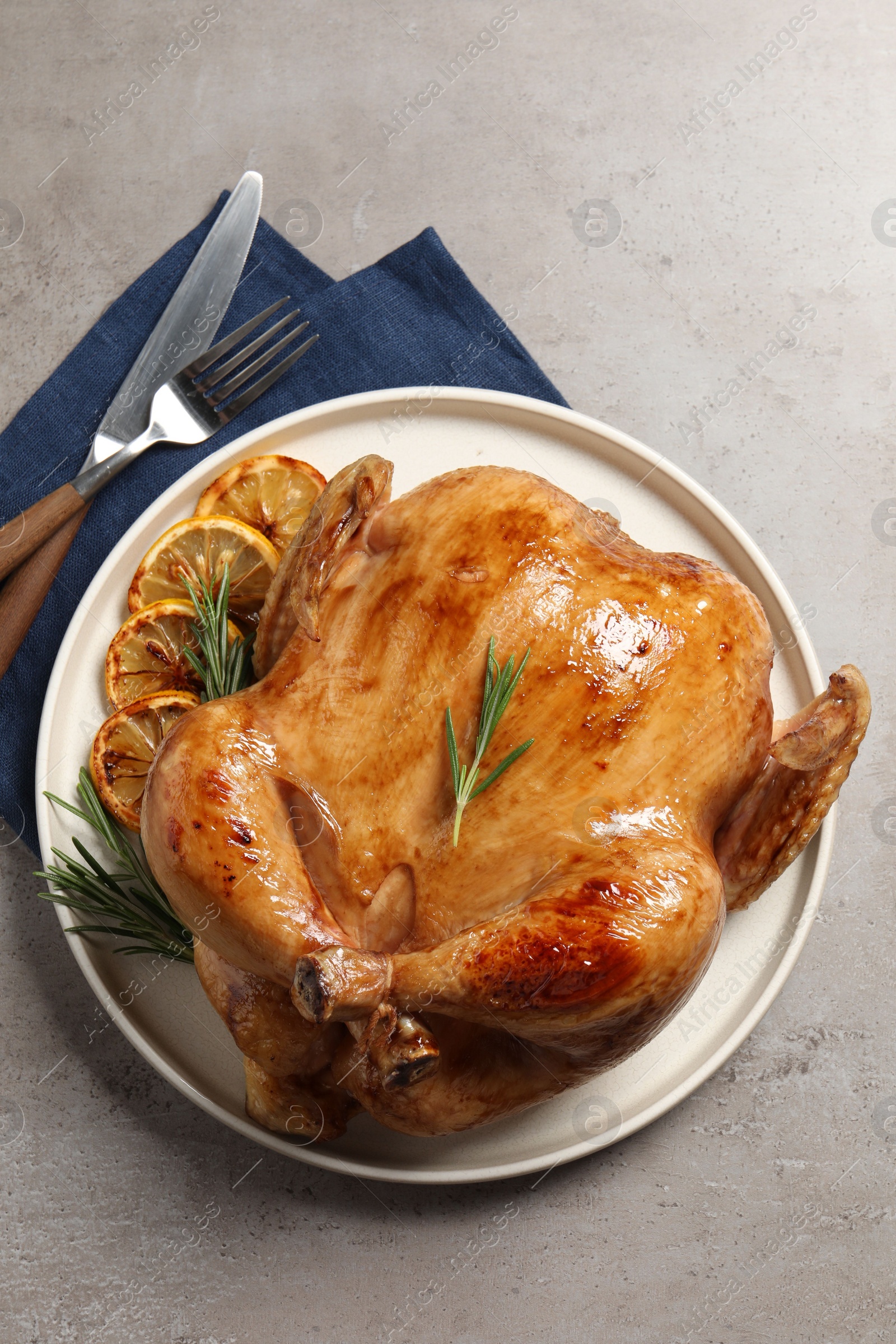 Photo of Tasty roasted chicken with rosemary and lemon served on light grey table, flat lay