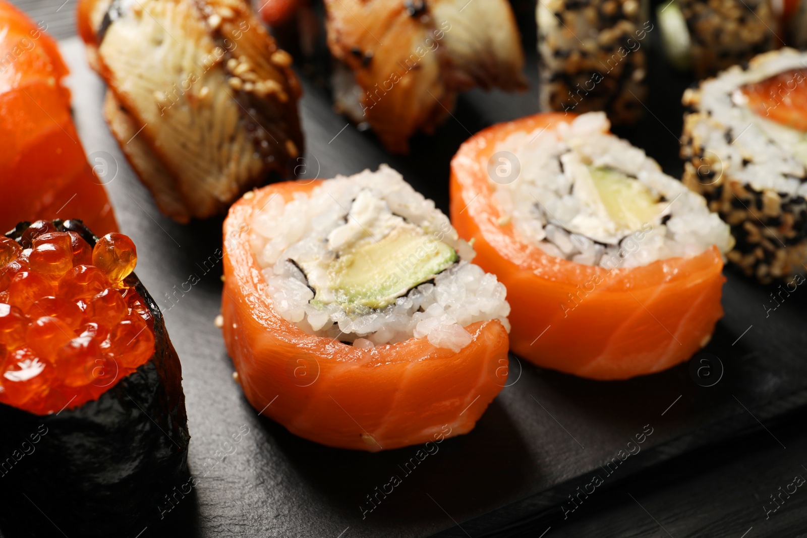 Photo of Set of delicious sushi rolls on black table, closeup