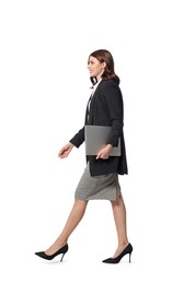 Happy young businesswoman with laptop walking on white background