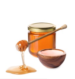 Natural honey dripping from dipper. Jar full of honey and bowl on white background