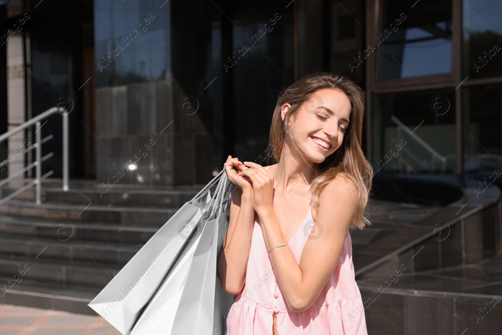 Photo of Happy young woman with shopping bags outdoors