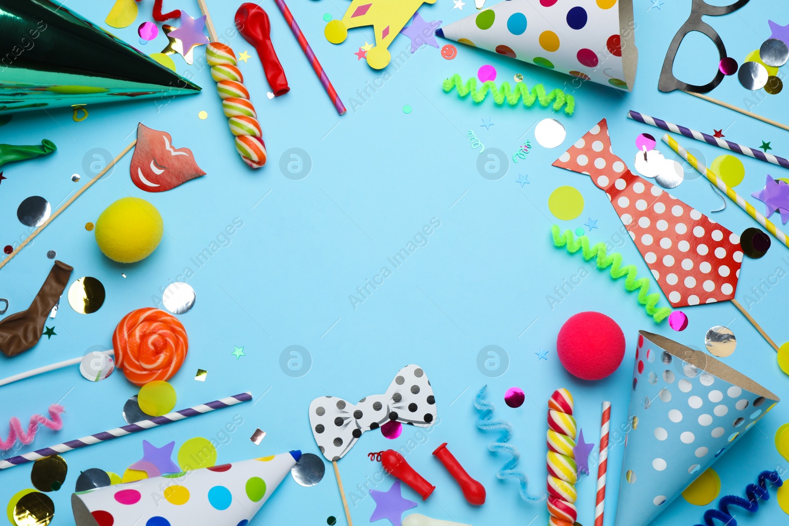 Photo of Frame of party hats and other festive items on light blue background, flat lay with space for text. Birthday surprise