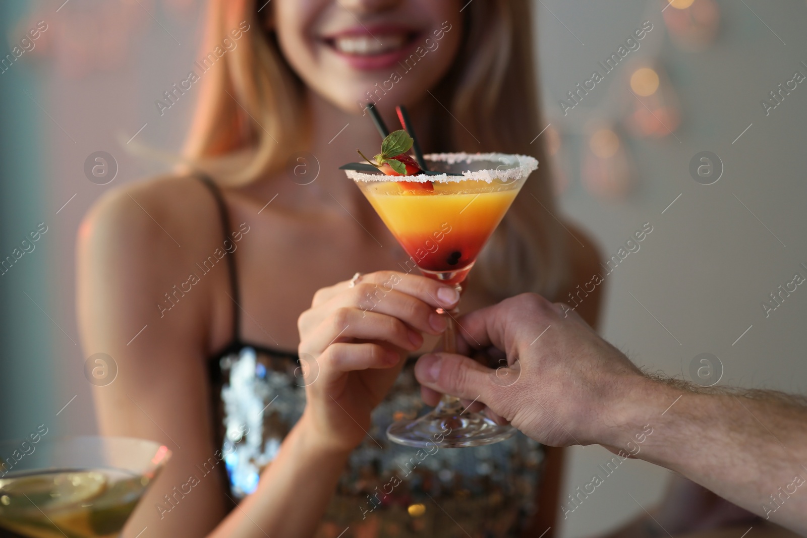 Photo of Young woman taking martini cocktail from barman at party, closeup