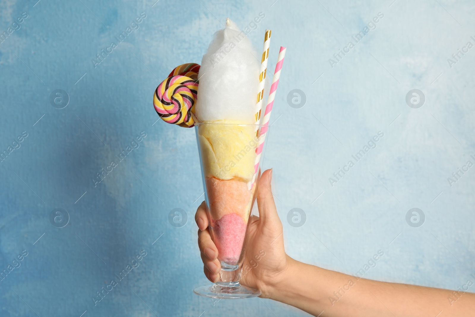 Photo of Woman holding glass with fluffy cotton candy on color background
