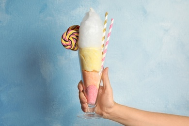 Photo of Woman holding glass with fluffy cotton candy on color background