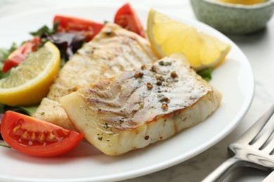 Photo of Tasty cod cooked served with salad on white table, closeup