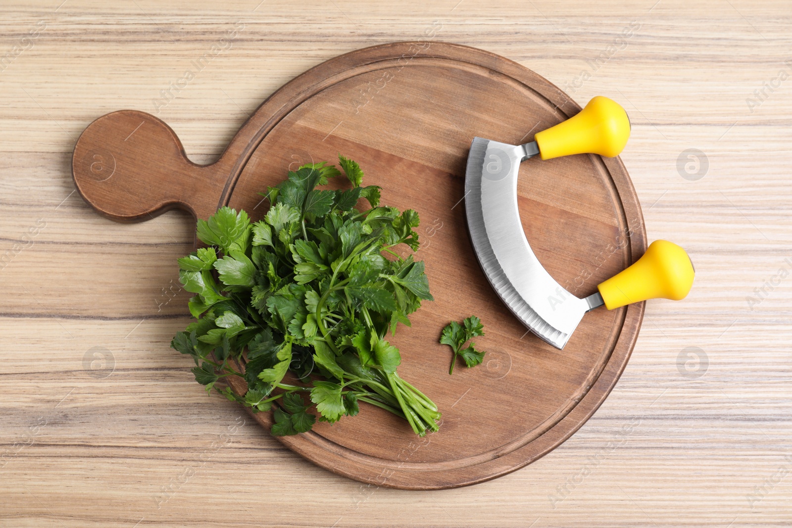 Photo of Composition with mezzaluna knife and bunch of parsley on wooden table, top view. Clean dishes