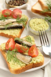 Photo of Delicious sandwiches with sprats, tomatoes, dill and avocado puree served on white wooden table