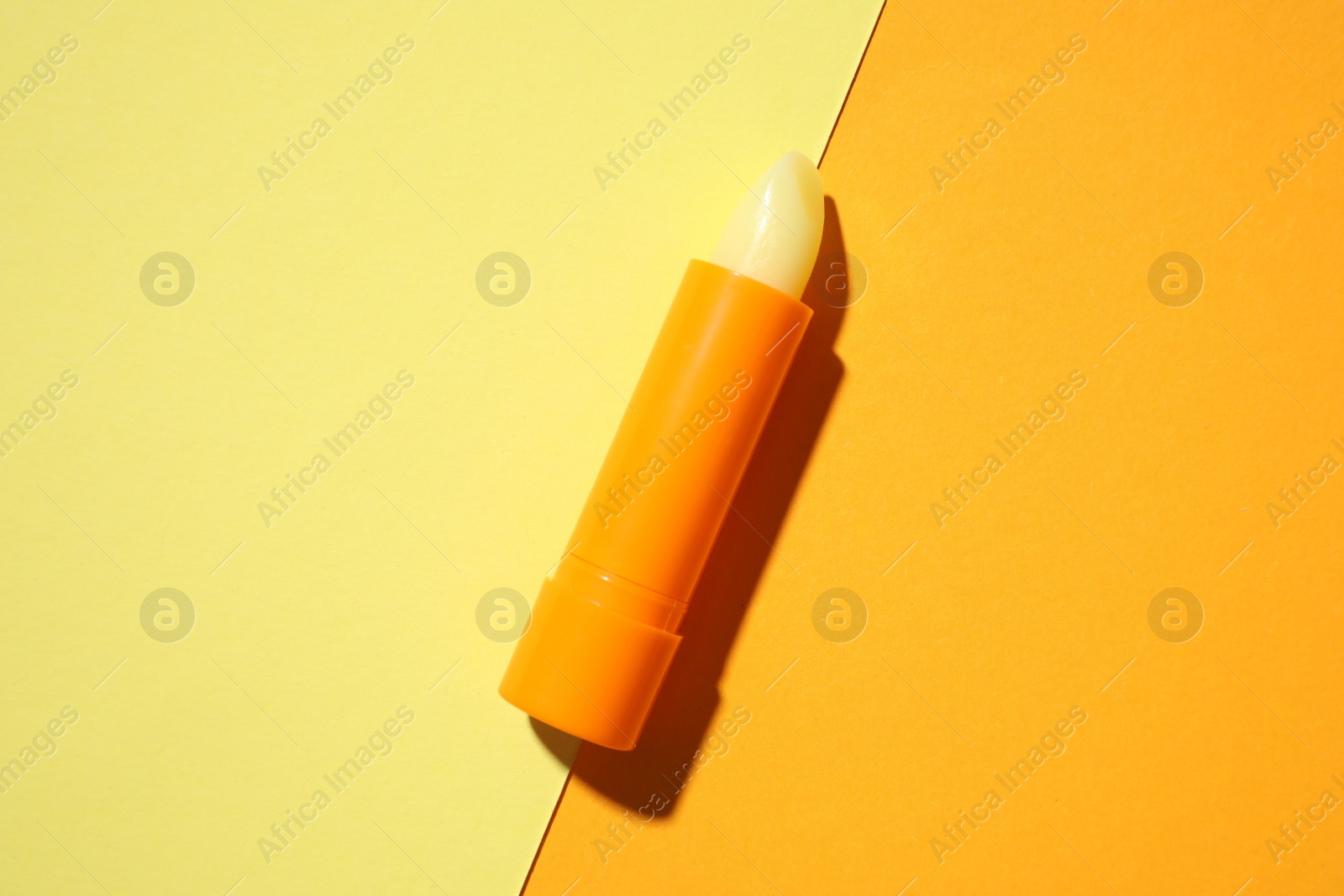 Photo of Hygienic lipstick on color background, top view