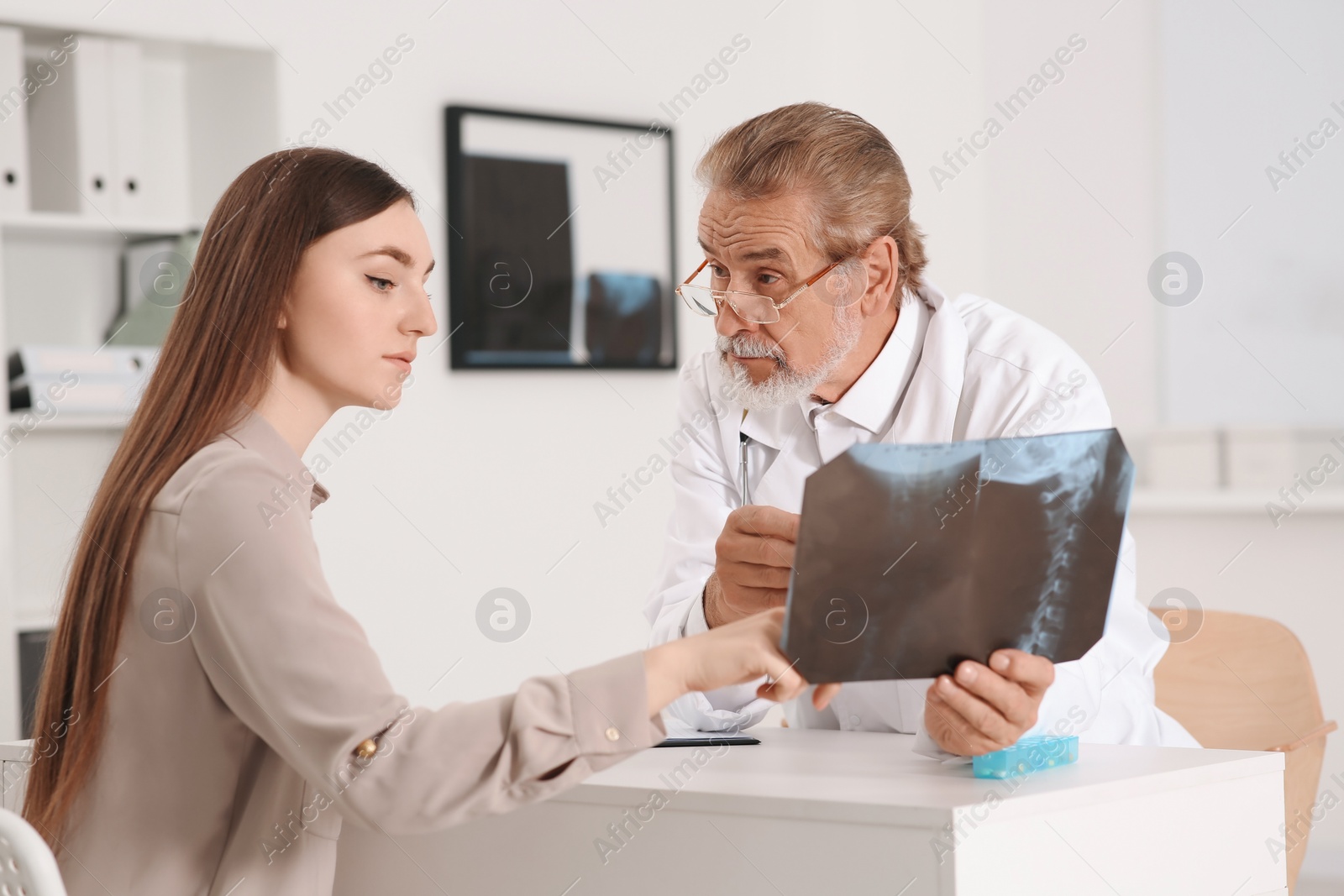 Photo of Orthopedist showing X-ray picture to patient in clinic