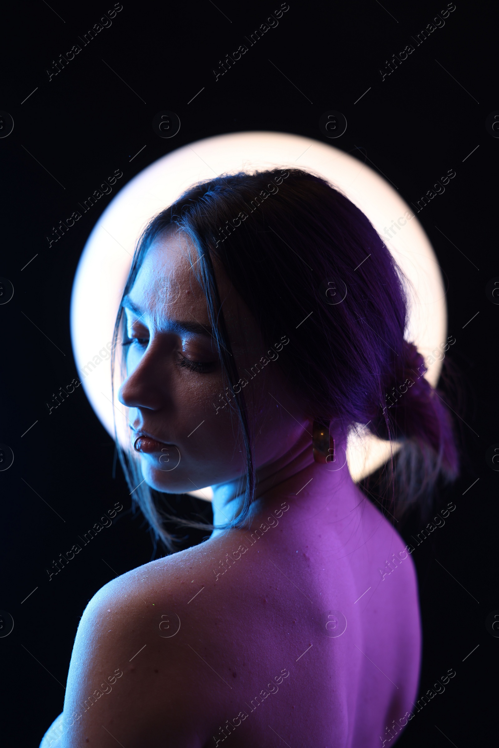 Photo of Beautiful woman and ring lamp on dark background in neon lights