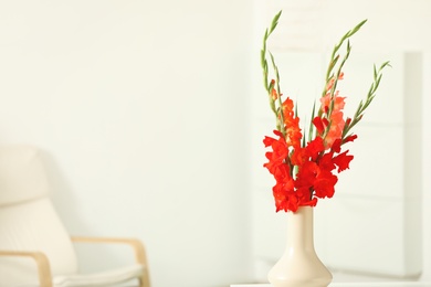 Photo of Vase with beautiful gladiolus flowers on wooden table indoors. Space for text