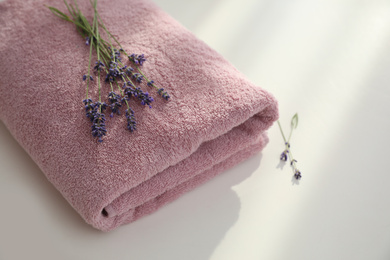 Folded clean towel and lavender flowers on white table, closeup