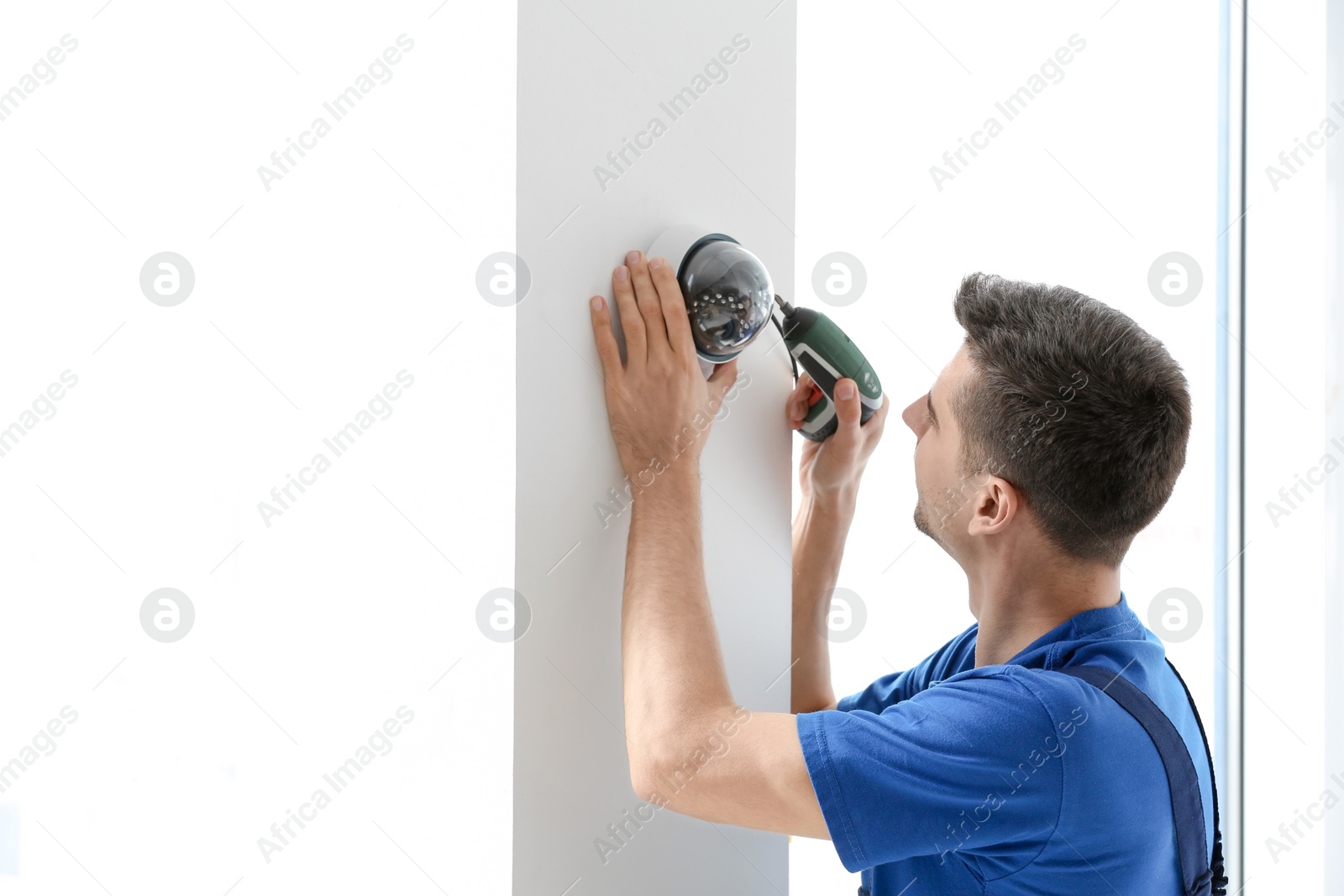 Photo of Technician installing CCTV camera on wall indoors