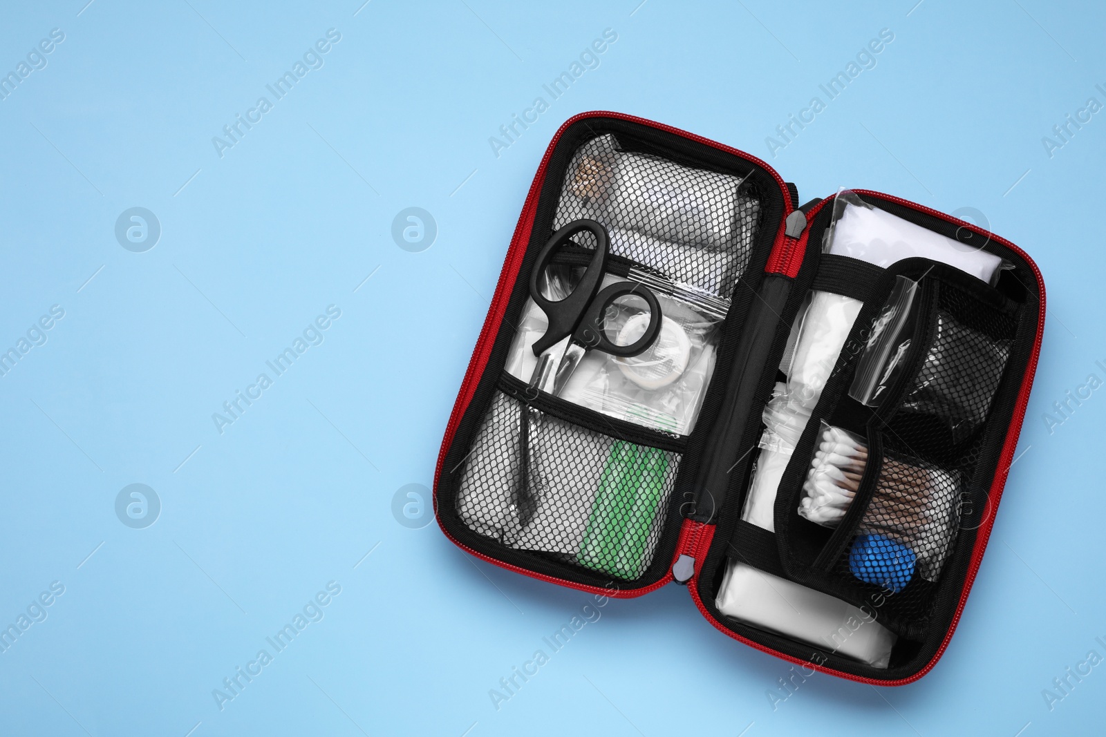 Photo of Open first aid kit on light blue background, top view. Space for text