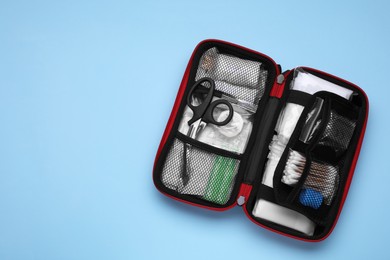 Photo of Open first aid kit on light blue background, top view. Space for text